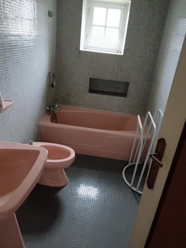 La salle de bains est pourvue d'une baignoire rose, de toilettes et d'un lavabo. dans l'établissement Ty Coz, à Carhaix-Plouguer