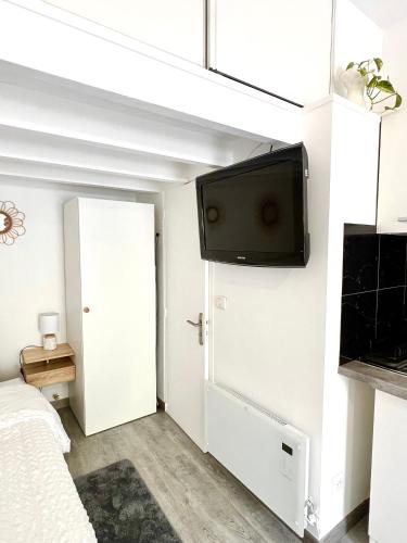 Cette chambre comprend un lit et une télévision murale à écran plat. dans l'établissement Cocon des Alouettes, à Montmorency