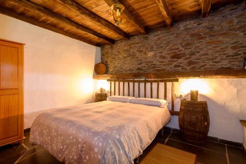 a bedroom with a bed and a stone wall at As Casias d'Oscos in Villanueva de Oscos