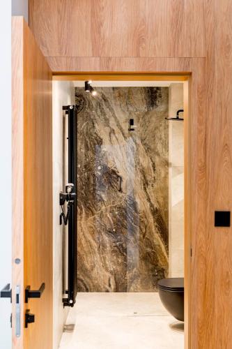 a bathroom with a toilet and a stone wall at Apartament Wood Design ED73341 in Białka Tatrzańska