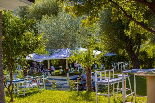a group of white chairs and tables in a park at Berat River House Boutique Hotel in Berat