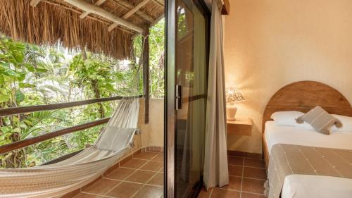 a room with a hammock and a bed and a window at Hotel Casa Colibri in Playa del Carmen