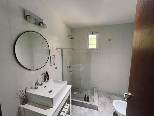 Un baño blanco con lavabo y espejo. en Casa Leo - Casa Con pileta en Zona Acantilados Para 4 PAX - Hola Sur, en Mar del Plata