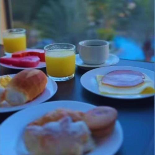 een tafel met borden ontbijtproducten en glazen sinaasappelsap bij Águas do Paranoá in Caldas Novas