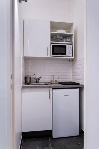 une cuisine avec des armoires blanches et un micro-ondes dans l'établissement Welcome to Cristina's House, à Paris