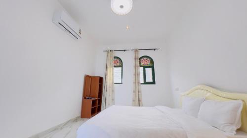 a bedroom with a white bed and two windows at Wadi shab Beach Resort in Sur
