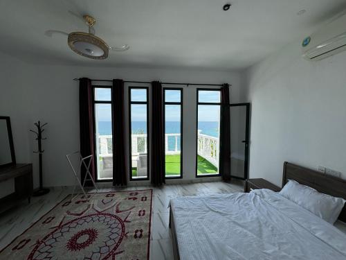 a bedroom with a bed and large glass doors at Wadi shab Beach Resort in Sur