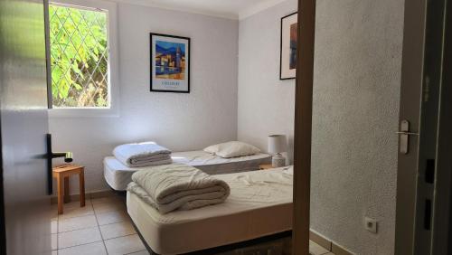 deux lits dans une chambre avec une fenêtre dans l'établissement Appart T3, quartier calme , idéal tout à pieds parking privé Résidence Cadenisse, à Collioure