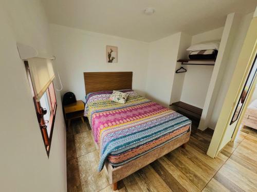 a small bedroom with a bed with a colorful blanket at Apartahotel Arcoiris Salento in Salento