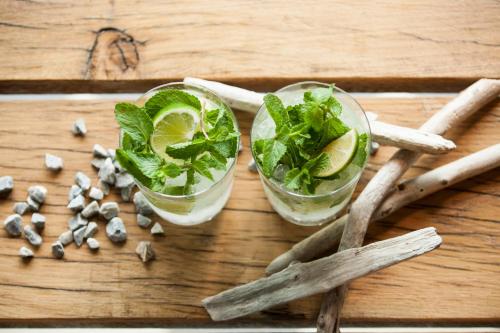 two cocktails with lime and mint on a wooden table at Hotel Katoen in Goes