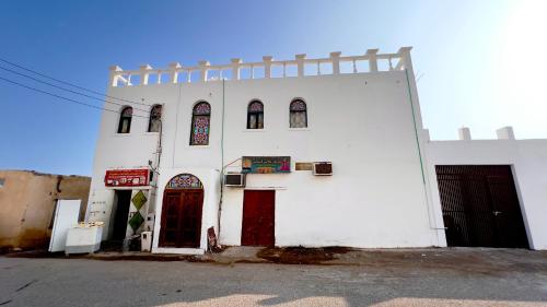 a white building with red doors and windows at Wadi shab Beach Resort in Sur
