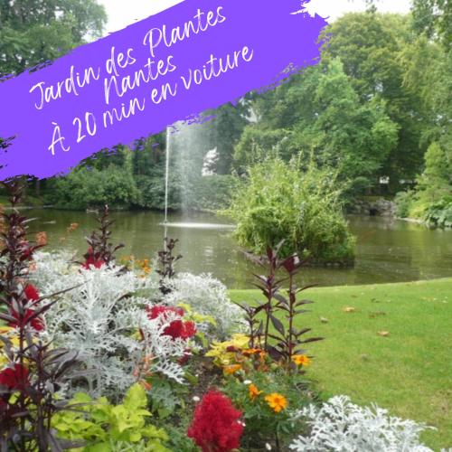 a garden with flowers and a pond in the background at Charmant T2 , en bord de Sèvre in Vertou