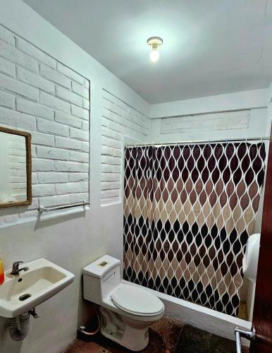 a bathroom with a white toilet and a sink at Jaco Mizata Beach and River in Las Piedras