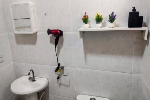 a bathroom with a sink and a toilet and flowers at Residencial Carvalho AP 1 in Torto