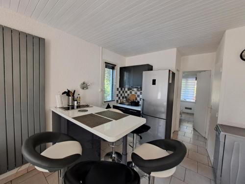 une cuisine avec des chaises noires et un comptoir blanc dans l'établissement Cottage au cœur des Landes, à Lit-et-Mixe