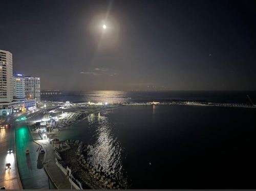 a view of a beach at night with the moon at Nour 1 in Alexandria