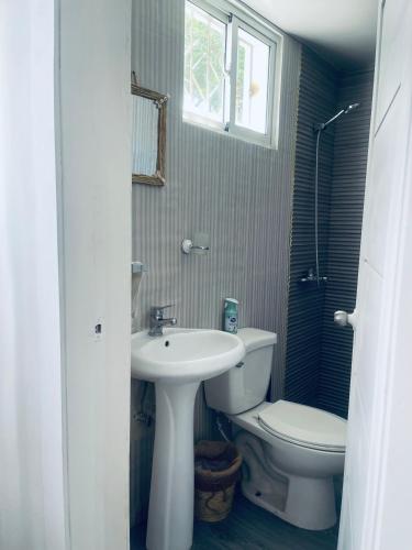 ein Badezimmer mit Waschbecken, Toilette und Fenster in der Unterkunft A Caribbean-style rebirth, 2 minutes from the beach in La Romana