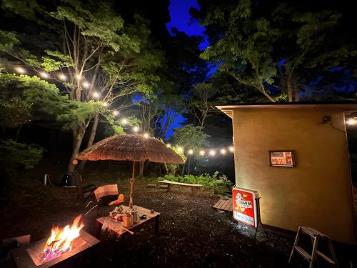 a fire pit with an umbrella and a table at Sakazuki Forest Bump in Higashiizu