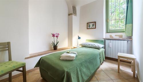 a bedroom with a green bed with towels on it at Domus Colonnato su Villa d'Este in Tivoli