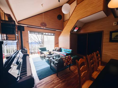 a living room with a piano and a table at Sakazuki Forest Bump in Higashiizu