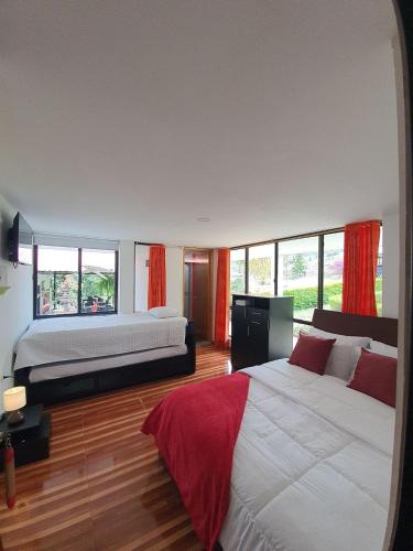 a bedroom with two beds with red curtains at Hotel & restaurante campestre la siria in San Juan de Rioseco 