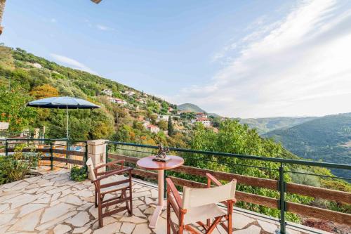 a patio with a table and chairs and an umbrella at Mountain Oasis - Pool & Playground near Neda Falls in Kalítsaina