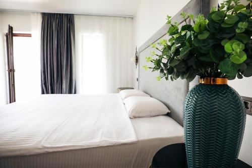 a bedroom with a bed and a vase with a plant at Pensiunea Berzasca in Berzasca