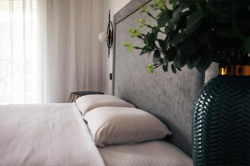 a bed with two pillows and a vase with a plant at Pensiunea Berzasca in Berzasca