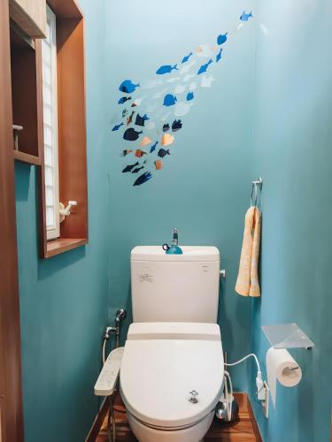 a bathroom with a toilet with fish on the wall at Sakazuki Forest Bump in Higashiizu
