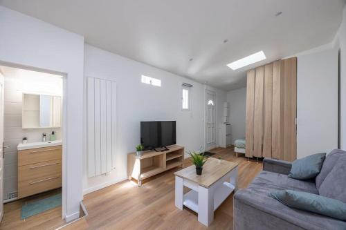 un salon avec un canapé et une télévision dans l'établissement Studio Cosy Terrasse au Calme CDG Disney, à Chelles