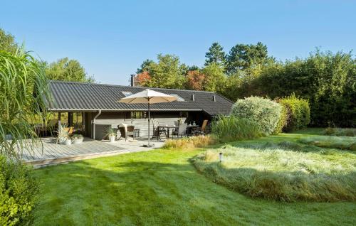 a house with a patio and an umbrella at Awesome Home In Føllenslev With Wifi in Føllenslev