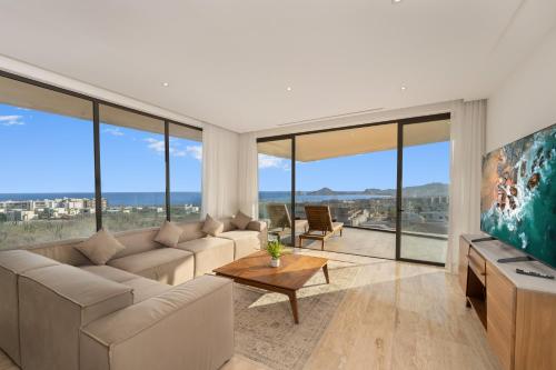a living room with a couch and a tv and large windows at Mistiq Los Cabos in Cabo San Lucas