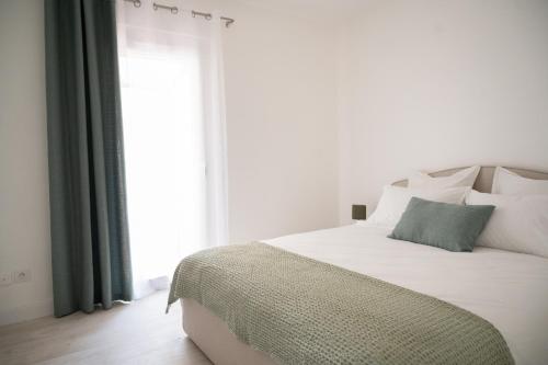 - un lit blanc avec une couverture verte et une fenêtre dans l'établissement Loustalot - Appartement lumineux 3 chambres - Parking Gratuit, à Béziers