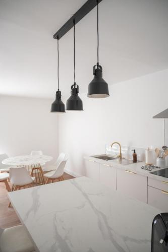 une cuisine blanche avec un évier et une table dans l'établissement Loustalot - Appartement lumineux 3 chambres - Parking Gratuit, à Béziers