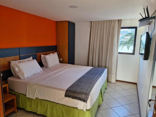 a bedroom with a large bed with an orange wall at Hotel Natal Plaza com piscina, academia, 100m da praia de Ponta Neg in Natal