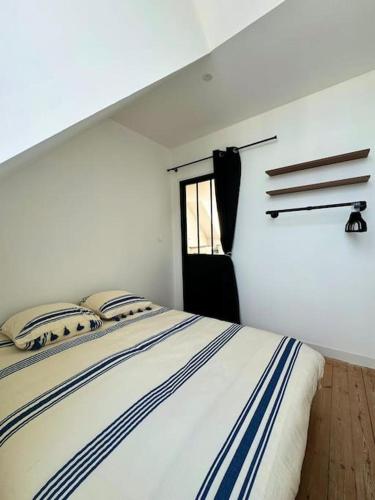 un lit dans une chambre blanche avec une fenêtre dans l'établissement Chez Alice - 100m de la plage, à Bénodet