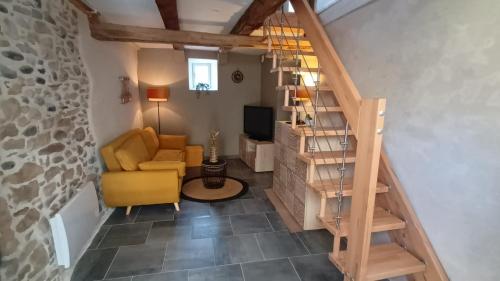 a living room with a staircase and a yellow chair at La Marquise in Saint-Côme-dʼOlt