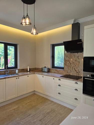 a large kitchen with white cabinets and windows at Villa Mulberry, Kyrenia in Kérynia