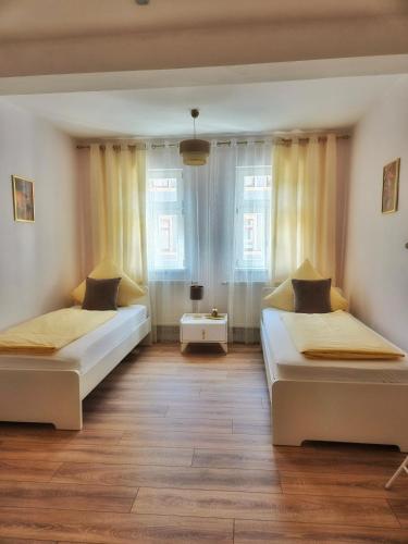two beds in a room with two windows at Appartements am Bachhaus in Eisenach