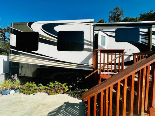an rv is parked next to a wooden deck at Happy Hedgehog River Views Hot Tub Private in Ahwahnee