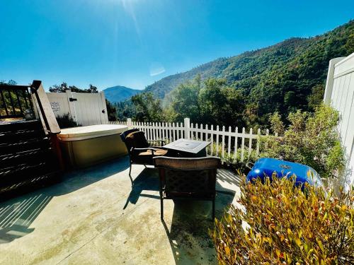 a table and chairs on a patio with mountains in the background at Happy Hedgehog River Views Hot Tub Private in Ahwahnee