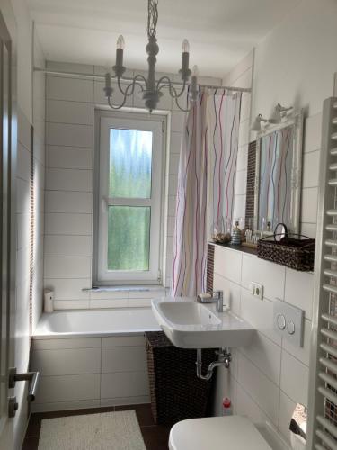 a bathroom with a sink and a tub and a window at FeWo Villa Haase in Ostorfer Hals