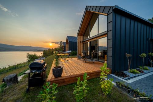 a house with a grill on a deck next to the water at Mucharskie Zacisze in Zagórze