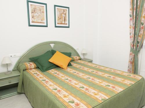 a bedroom with a bed with green and yellow pillows at Turquesa Beach Unitursa in Calpe