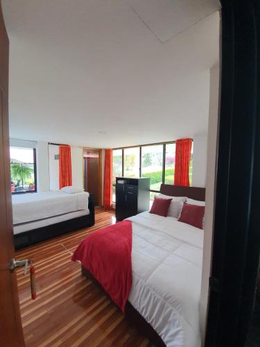 a bedroom with two beds and a large window at Hotel & restaurante campestre la siria in San Juan de Rioseco 