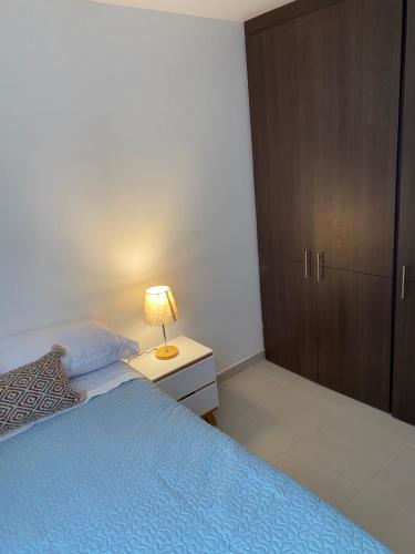 a bedroom with a bed and a lamp on a night stand at Apartamento en Floridablanca Santander in Loma Mesa de Ruitoque