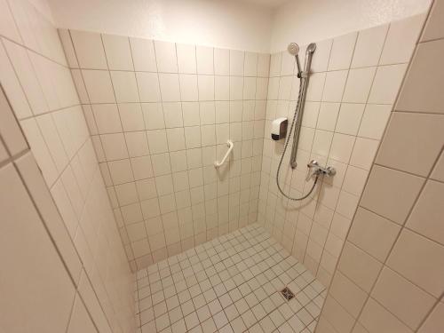 a bathroom with a shower with white tiles at Aparthotel B & L in Bremen