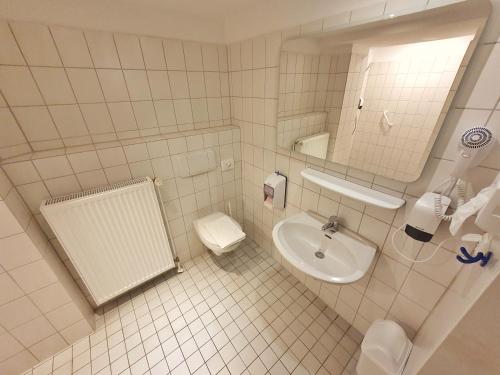 a white bathroom with a sink and a toilet at Aparthotel B & L in Bremen