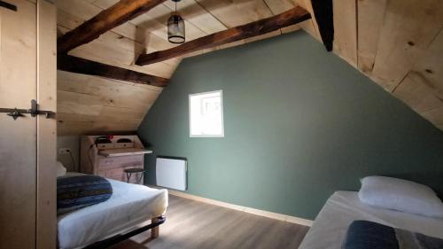 Cette chambre mansardée comprend 2 lits et un mur vert. dans l'établissement La Marquise, à Saint-Côme-dʼOlt