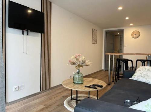 un salon avec un vase de fleurs sur une table dans l'établissement Appartement tout confort, à Cambrai
